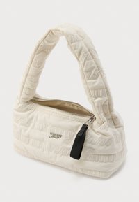 Bolso de hombro acolchado color crema con texto acolchado "Tommy Jeans", placa de logo plateada y cremallera parcialmente abierta con tirador negro.