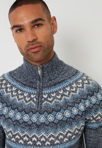 Maglione con zip e collo alto, grigio e blu, caratterizzato da una trama intrecciata elaborata e disegni geometrici.