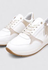 Zapatillas blancas con detalles en beige, con diseño de cordones, material de cuero liso, cierre de cremallera y suela de goma.