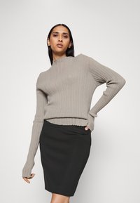 Grauer gerippter Pullover mit hohem Kragen und langen Ärmeln, kombiniert mit einem schwarzen Bleistiftrock. Glatte Textur und figurbetontes Design.