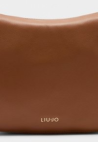 Pruun tekstuuriga nahast käekott, mille alumises osas on kullakarva "LIU-JO" logo. Kott on ümarate servadega ja tõmblukuga.