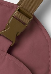 Boucle en plastique marron sur un tissu mauve texturé, avec des coutures soignées et un bord arrondi, mettant en avant un design robuste et la qualité des matériaux.