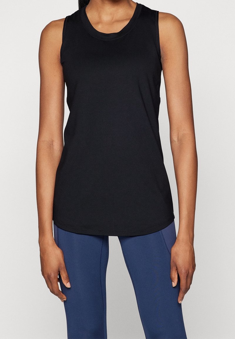 Débardeur de sport noir sans manches avec un col rond, une texture subtile et une coupe ajustée, associé à des leggings bleu marine.