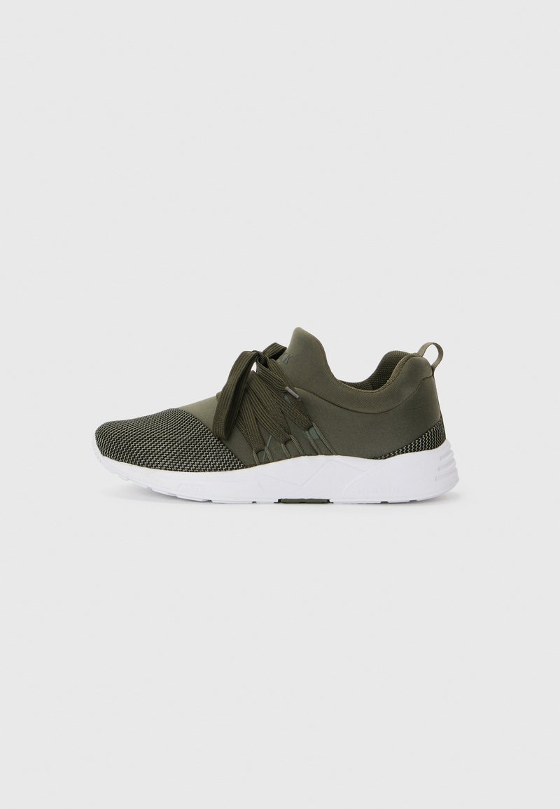 Chaussure de sport vert olive avec tissu en maille et tricot texturé, dotée d'une semelle blanche et d'un système de laçage, conçue pour le confort et le support.