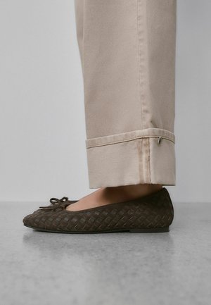 Brune, vævede flade sko med rund tå og bueaccent, kombineret med lyse beige bukser med opklemmede manchetter og en sidesømsdetalje.