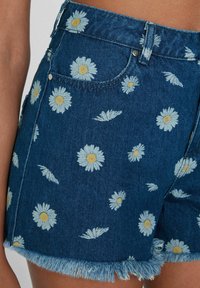 Szorty dżinsowe w ciemnoniebieskim odcieniu, z motywem kwiatów stokrotek i postrzępionym wykończeniem. Zawierają kieszenie z przodu oraz zamek błyskawiczny.
