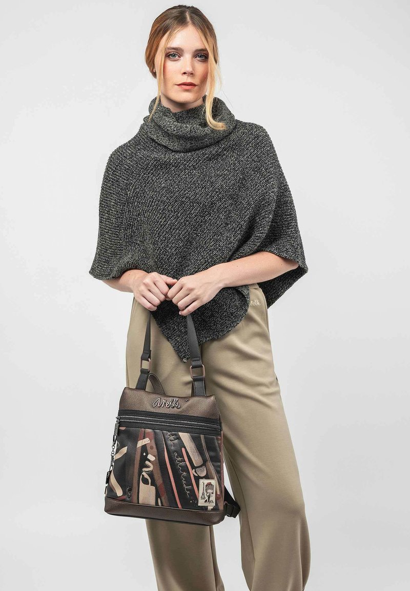Bolso de hombro marrón y negro con un diseño de materiales mixtos, cremalleras y patrones impresos. El bolso tiene correas cortas y un acabado texturizado.