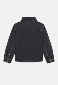 Μαύρο τζάκετ από τζιν με μακριά μανίκια, γιακά και κουμπωτές μανσέτες. Διαθέτει εμφανή ραφή και καθαρό, μινιμαλιστικό σχέδιο στην πλάτη.