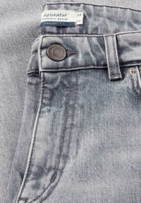 Grey organic denim jeans with a straight fit. Features a metal button, contrasting stitching, and a label with size information.