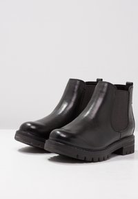 Zwarte enkelboots met een gladde leren afwerking, elastische zijpanelen en een gestructureerde rubberen zool. Ronde neus en lage blokhak.