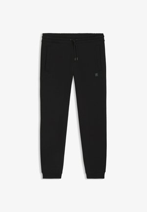 Pantaloni della tuta neri realizzati in tessuto morbido, dotati di una vita elastica con coulisse, tasche laterali e una piccola etichetta con logo.