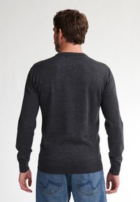 Pulover lung cu mânecă dintr-o nuanță gri închis, cu decolteu rotund, fabricat dintr-un material moale. Partea din spate are un design curat, fără logo-uri sau caracteristici proeminente.