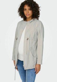 Světle šedá mikina s kapucí vyrobená z hladké tkaniny, s elastickými šňůrkami, zipem vpředu a dvěma bočními kapsami. Dlouhé rukávy s uvolněným střihem.