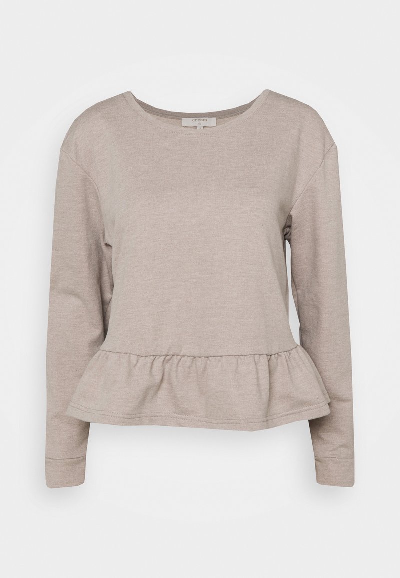 Top beige à manches longues pour femme avec encolure ronde et bas à volant, en tissu tricoté doux.