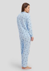 Conjunto de pijama azul claro hecho de tejido suave, con un estampado de pequeñas flores azules oscuras. Camiseta de manga larga con puños acanalados y pantalones a juego.