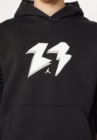 Felpa nera con cappuccio, decorata con un grande numero "23" stilizzato in bianco e un piccolo logo Jumpman centrato sotto i numeri.