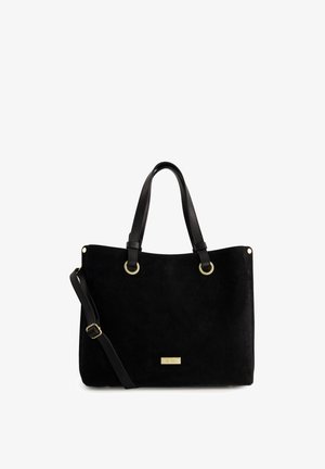 Black suede tote bag with dual black handles, gold hardware accents, and adjustable shoulder strap. Features a metallic logo plate.