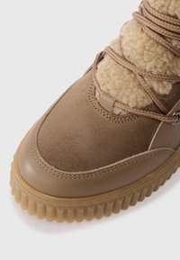 Barna sneaker velúr és bőr felsőrésszel, bolyhos béléssel és bordázott gumitalppal. Kézműves fűzőkkel és fém szemekkel rendelkezik.