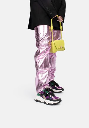 Pantaloni metallici rosa, blazer nero e sneakers multicolori. Piccola borsa gialla tenuta a mano. Tessuto testurizzato con lucentezza.