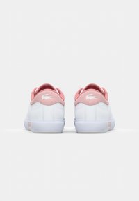 White sneakers with pink accents, featuring a smooth leather upper, rounded shape, cushioned heel, and textured rubber sole.