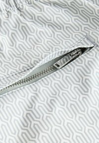 Light gray fabric with a geometric pattern featuring interlocking lines. Exposed silver zipper on one seam. Smooth texture, soft finish.
