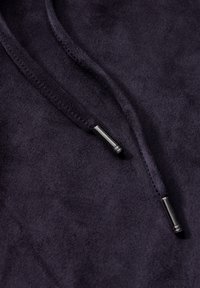Donkerpaarse sweatshirtstof met een zachte textuur, voorzien van een trekkoord met metalen aglets. Close-up weergave die de details accentueert.
