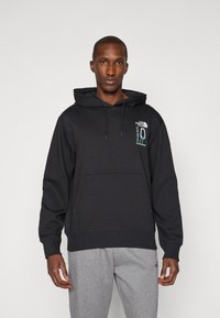 Sweatshirt preto com capuz e bolso frontal, feito de tecido macio. Apresenta um logótipo bordado no peito e cordões ajustáveis.
