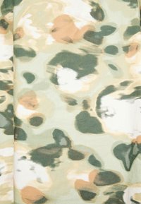 Tecido leve com um padrão de camuflagem em tons de verde, bege e branco. Textura suave com formas e manchas abstratas e mescladas.