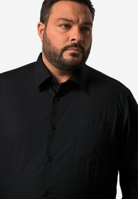 Zwart overhemd met een klassieke kraag, lange mouwen, een borstzak en een subtiele textuur. Voorzien van knoopsluiting en rechte zoom.