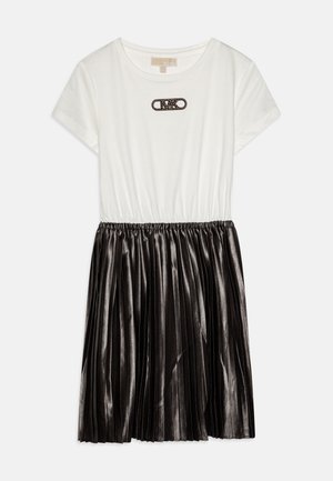 Robe à manches courtes avec un haut en coton blanc et une jupe métallique plissée noire, présentant un motif décoratif de broche sur la poitrine.