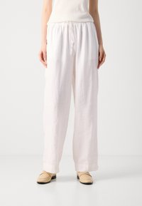 Pantalons en lin blancs avec une taille élastique et un cordon de serrage. Design ample avec des jambes larges, ourlées en bas.