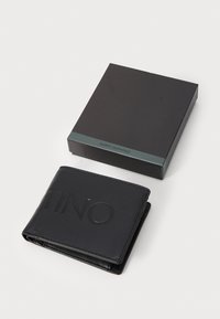 Portefeuille en cuir noir avec logo en relief, design pliable et coutures visibles. Accompagné d'une boîte noire avec une bande d'accent vert.