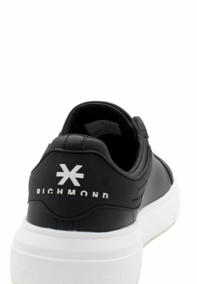 Sneaker nera in ecopelle con suola in gomma bianca. Presenta un logo sul tallone e un design minimalista con texture liscia e senza motivi.