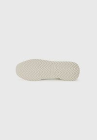 Sole di sneaker color crema con un motivo testurizzato a zigzag. Presenta un'etichetta di marca rettangolare con la scritta "Calvin Klein". Forma liscia e arrotondata.