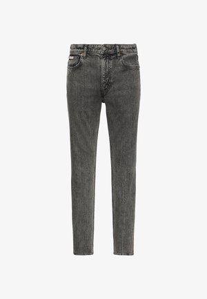 Slim-fit tuhmuksest mustad teksapüksid viie tasku, vöö aasade ja nööpidega taljel, eesvalgest taustast vaadatuna.