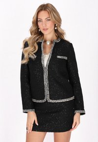 Sacou din tweed negru cu margini și accente argintii, având un design ajustat, mâneci lungi și o singură buzunar frontal.