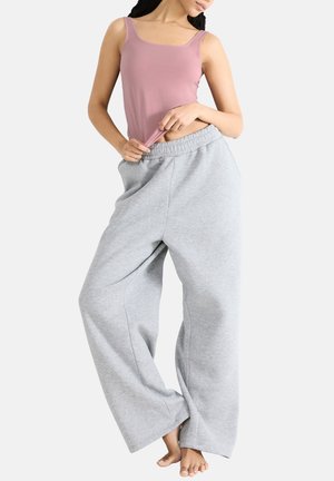 Lichtroze aansluitend tanktop met vierkante halslijn, gecombineerd met losse grijze sweatpants met een elastische tailleband en zijnaad.