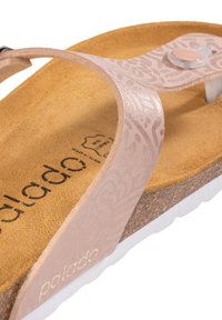 Ljusrosa sandal med dekorativ rem, korkfotbädd och vita gummisula. Har prägling och en cirkulär accentknapp.