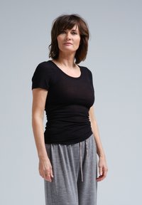 Mustat, slim fit -lyhythihainen t-paita kevyestä kankaasta, yhdistetty harmaisiin, löysiin housuihin, joissa on kiristysnyöri vyötäröllä.
