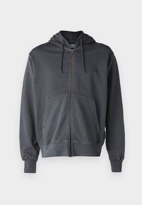 Felpa grigia con zip, cappuccio, tasche a marsupio anteriori, polsini a costine e una superficie liscia. Presenta una zip in metallo e un design minimalista.