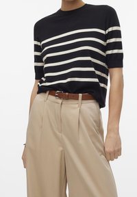 Granatowy prążkowany dzianinowy top z krótkimi rękawami, ozdobiony białymi poziomymi paskami. Połączony z beżowymi, wysokim stanem spodniami i brązowym paskiem.