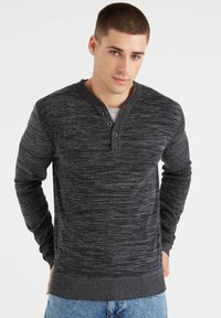Suéter de color gris oscuro con una superficie texturizada, escote tipo henley y tres botones como acentos. Mangas ajustadas y un dobladillo acanalado.