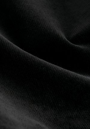 Svart tyg med en mjuk, texturerad yta. Materialet har subtila ribbor och en mild lyster som betonar djup och värme.