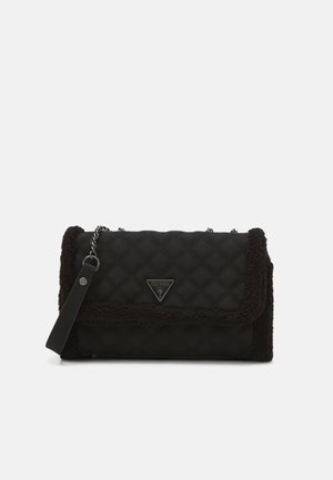 Borsa nera trapuntata con bordo in pelliccia sintetica, tracolla a catena e logo triangolare Guess sulla patta frontale.