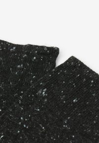 Tejido de punto negro con manchas azules, que presenta un acabado suave y texturizado. Los bordes están ligeramente deshilachados, mostrando un aspecto deshecho.