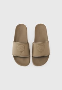 Brune sklisandaler laget av gummi med en teksturert stropp som har en preget karakterdesign foran og en jevn overflate.