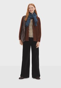 Brown corduroy jacket, checkered shirt, blue scarf, black wide-leg pants, and brown shoes. Smooth texture and layered design elements.