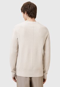Helle beige Strickpullover mit gerippten Bündchen und Saum. Verfügt über einen schlichten Rundhalsausschnitt und eine Nahtdetails auf der Rückseite. Weiche Textur.