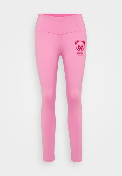 Rožinės legginsai, pagaminti iš lygios, tamprios medžiagos. Kairėje klubo pusėje yra lokio logotipas ir raudonas prekės ženklas. Aukšta liemens forma.