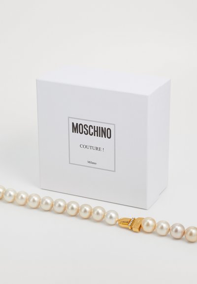 Bijela kutija Moschino Couture Milano s bisernom ogrlicom koja ima zlatnu kopču ukrašenu sitnim kristalima.